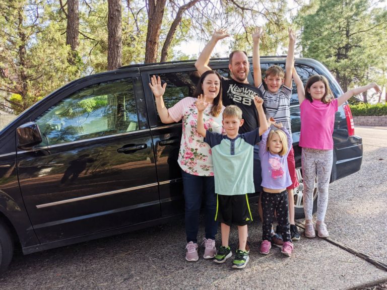family in front of black minivan